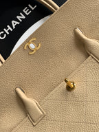 Beige pebbled Chanel leather bag front with gold CC hardware and strap tab
