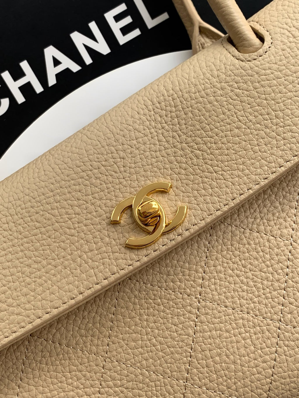 Beige pebbled leather Chanel flap-style detail with gold CC logo clasp