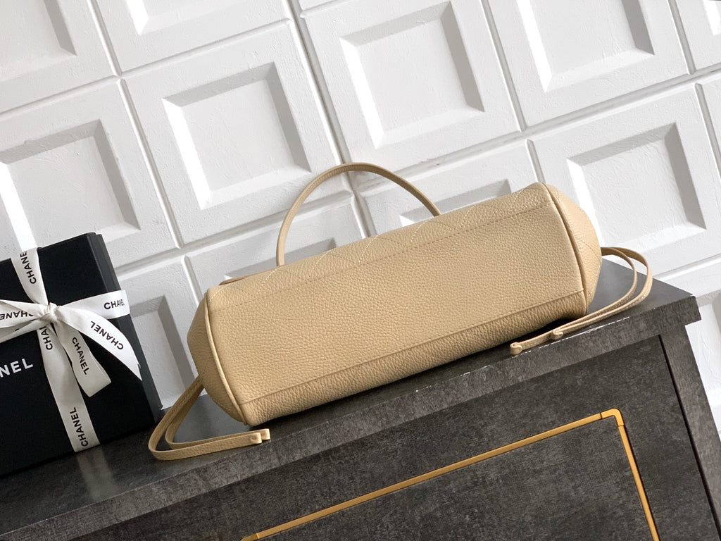 Beige Chanel leather handbag with shoulder strap and gold-tone clasp on tabletop