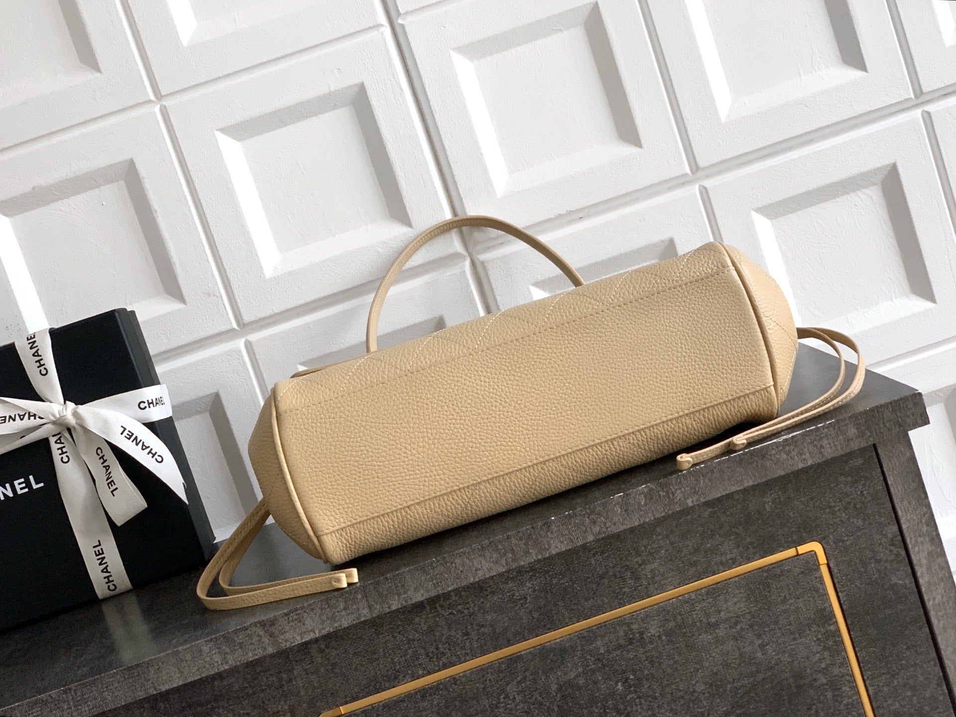 Beige Chanel leather handbag with shoulder strap and gold-tone clasp on tabletop