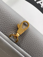 Chanel bag keyring pull tab with gold hardware on light gray leather