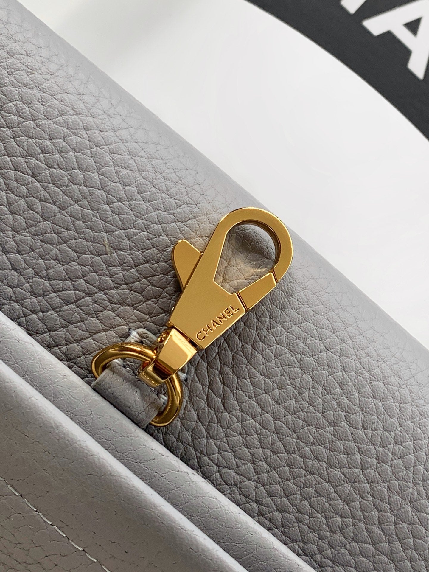 Chanel bag keyring pull tab with gold hardware on light gray leather