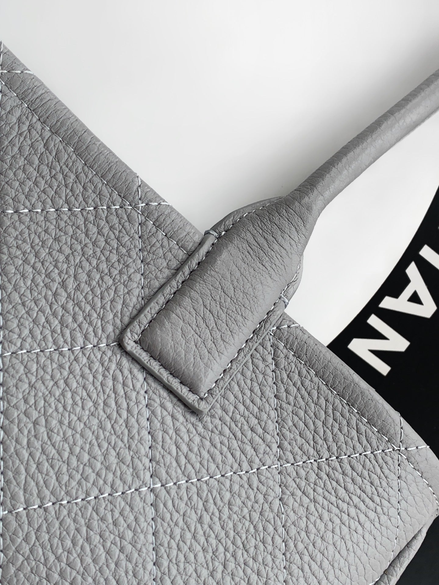 Chanel light gray leather bag corner with quilted stitching and metal frame detail