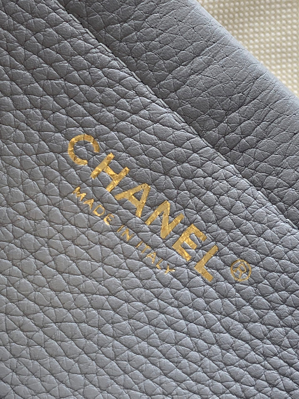 Chanel logo embossing on light gray quilted leather with gold lettering