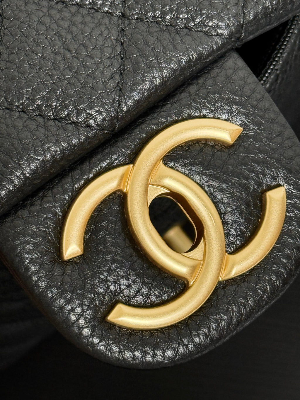 Gold-tone Chanel CC logo on black leather bag