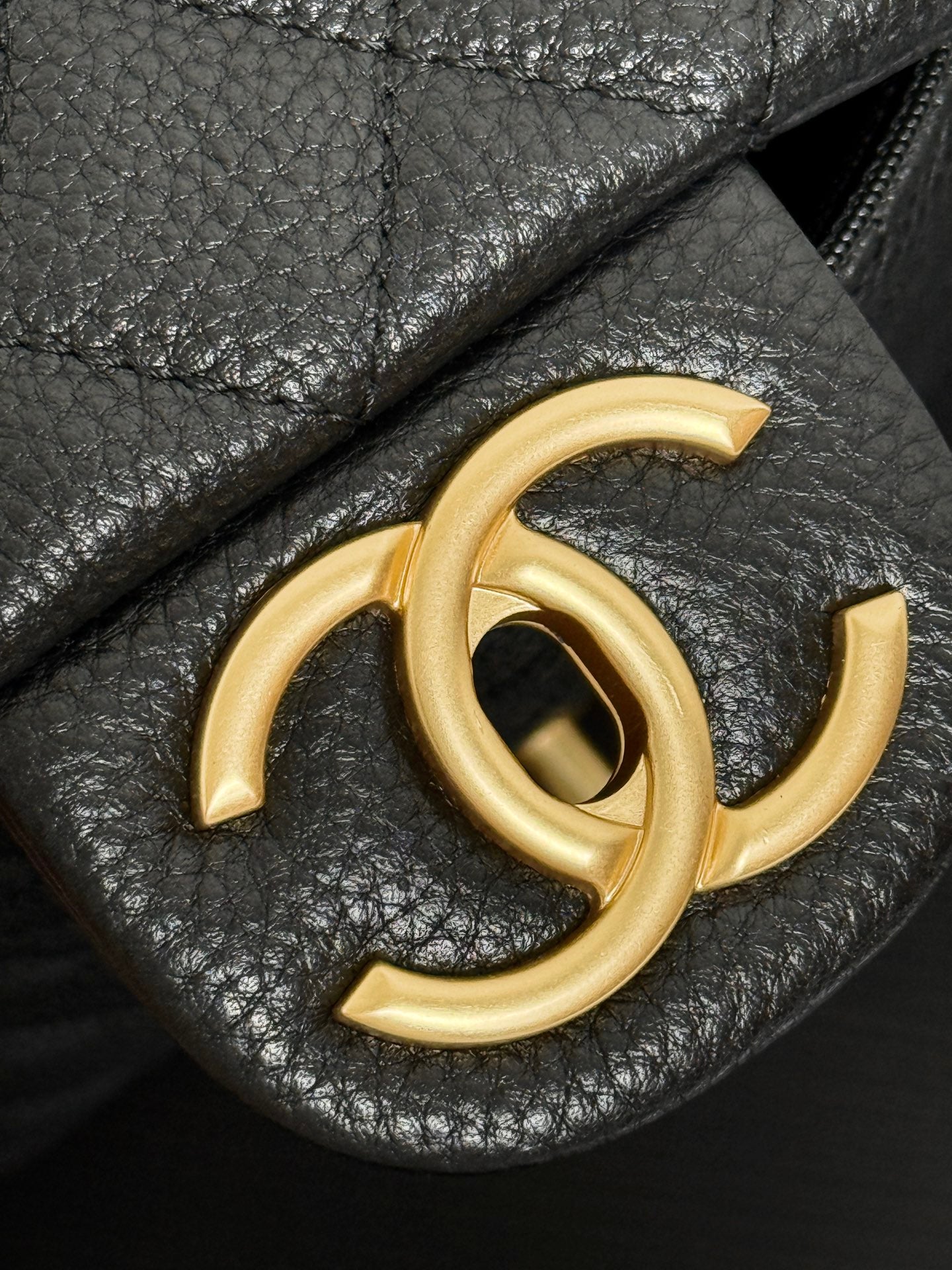 Gold-tone Chanel CC logo on black leather bag