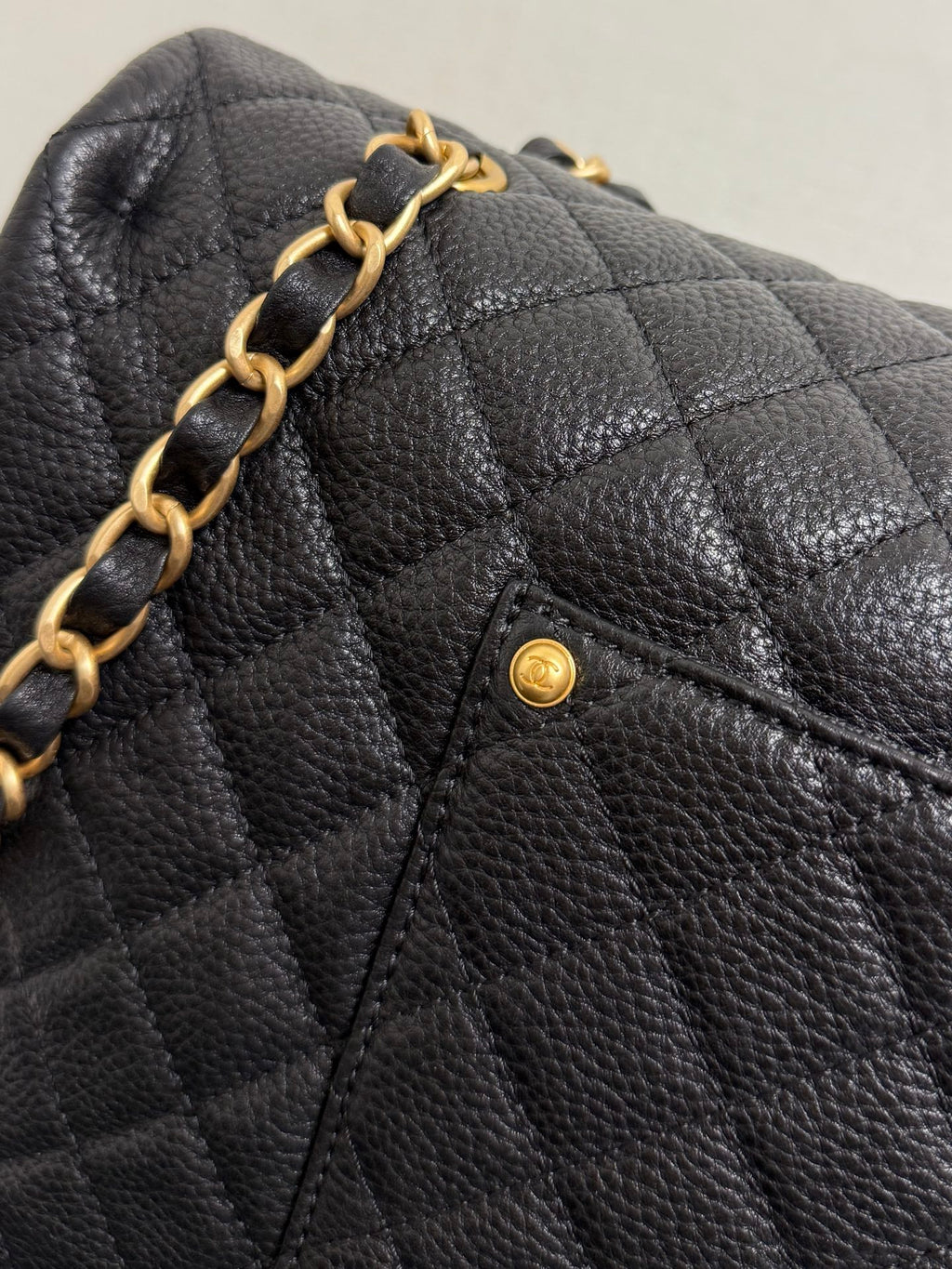 Black quilted Chanel flap with gold chain detail and small CC pin