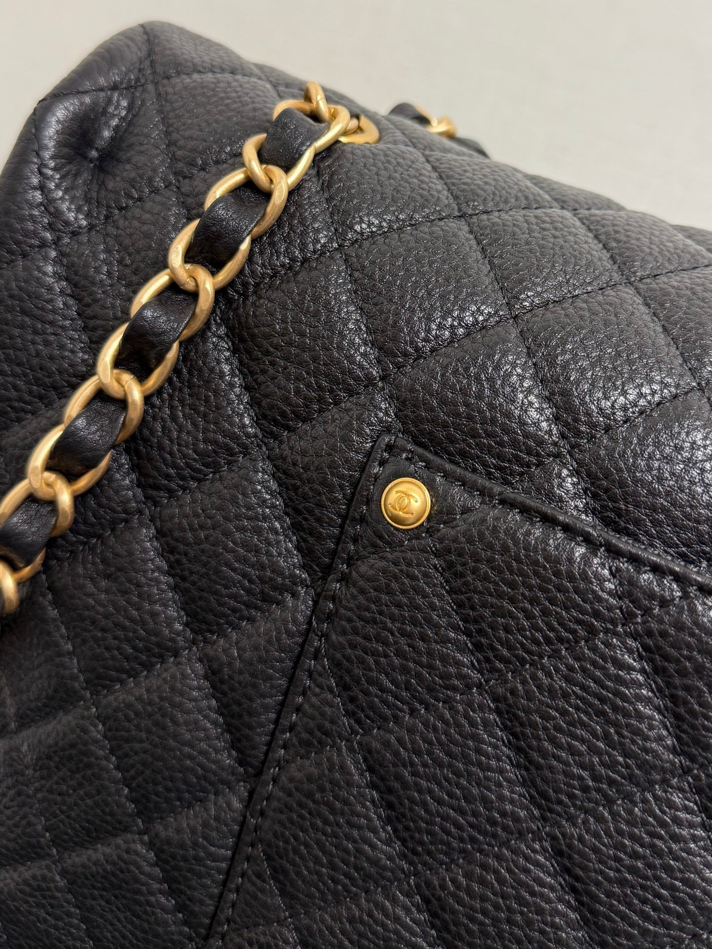 Black quilted Chanel flap with gold chain detail and small CC pin