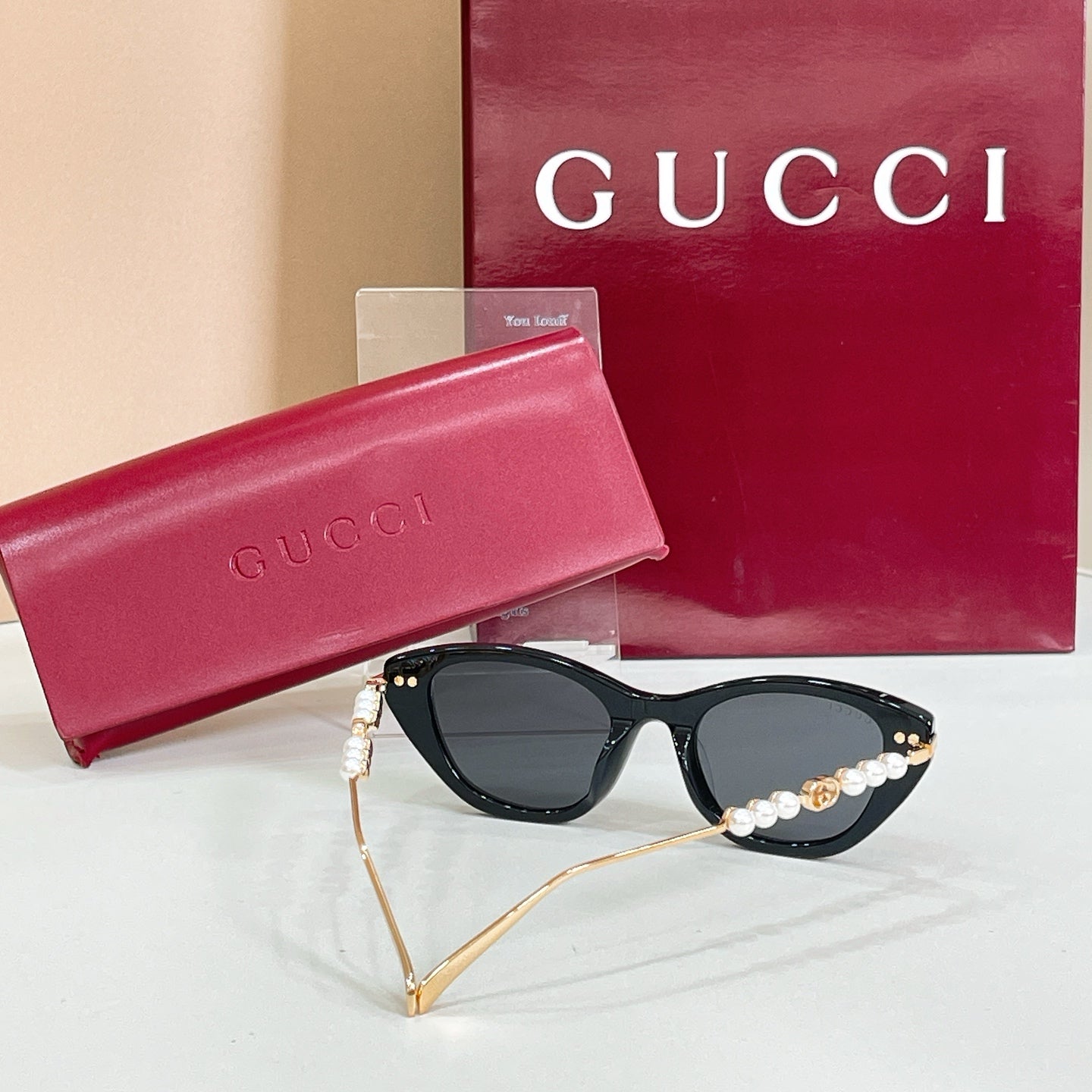 Sunglasses with black lenses, glossy dark frames, and pearl gold temple trim