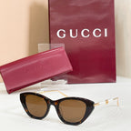 Sunglasses with dark lenses, tortoise-style frames, and gold-tone temple tips