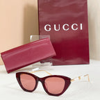 Sunglasses with maroon frames, pink lenses, and gold-tone temple hardware