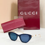 Gucci sunglasses with dark blue lenses, gold frames, and pearl detail on temples