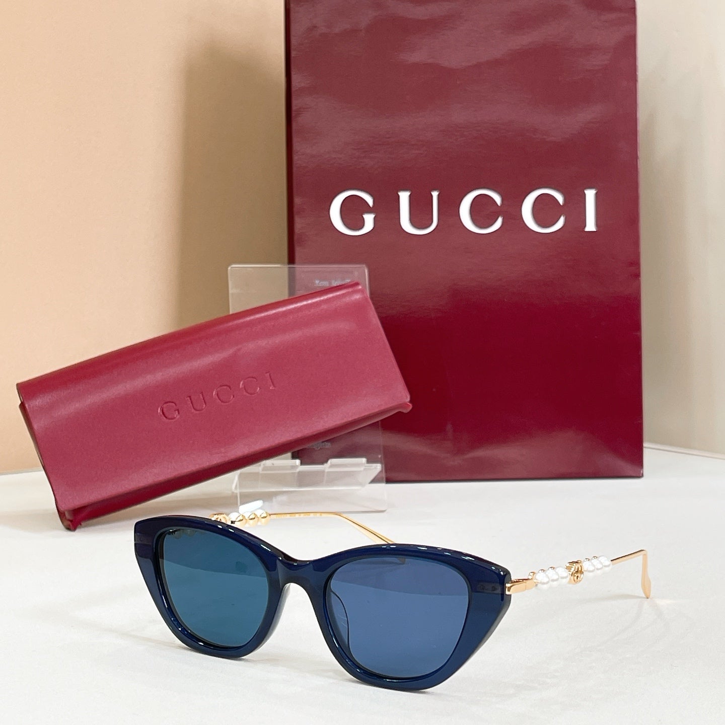 Gucci sunglasses with dark blue lenses, gold frames, and pearl detail on temples