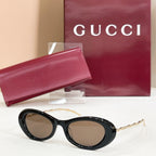 Gucci sunglasses, black round frames with brown tinted lenses and gold-tone arms