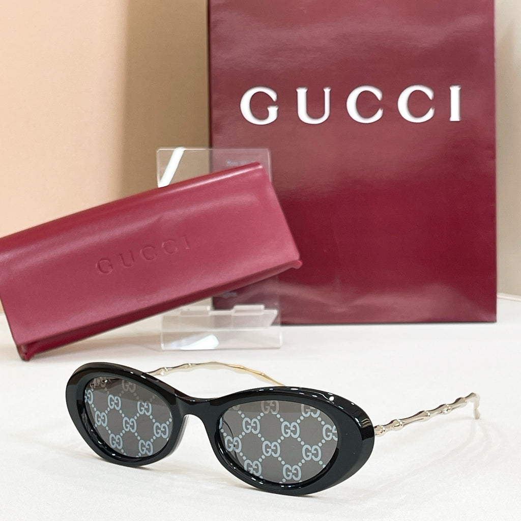 Gucci sunglasses, black round frames with GG-logo patterned lenses and gold-tone arms