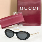 Gucci sunglasses, black round frames with dark gray lenses and gold-tone arms