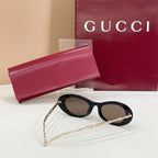 Gucci sunglasses with dark lenses and black oval frames, gold chain temples, in case