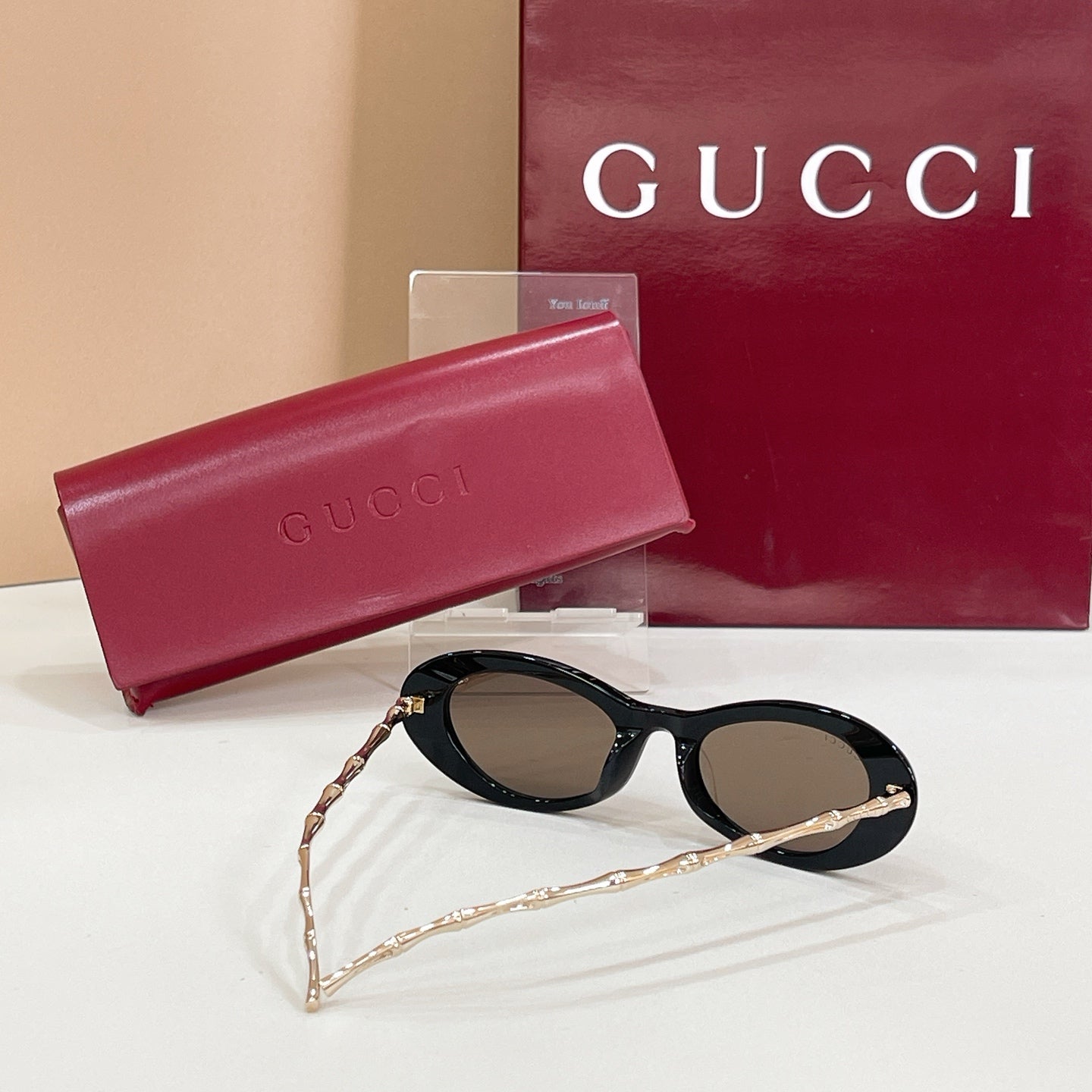 Gucci sunglasses with dark lenses and black oval frames, gold chain temples, in case