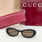 Gucci sunglasses with dark lenses and glossy black oval frames, gold temples