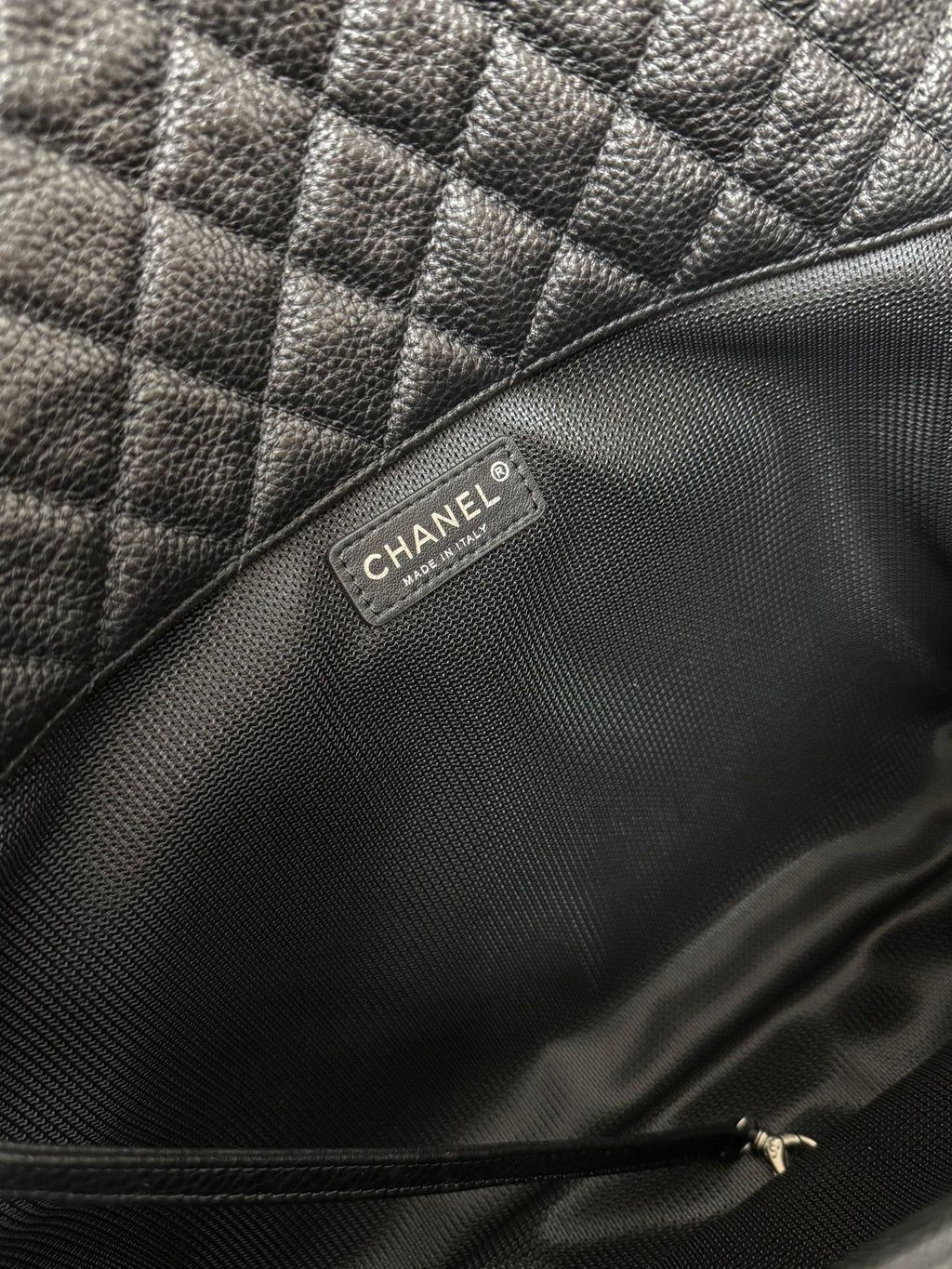 Chanel brand label inside dark quilted leather shoulder bag.