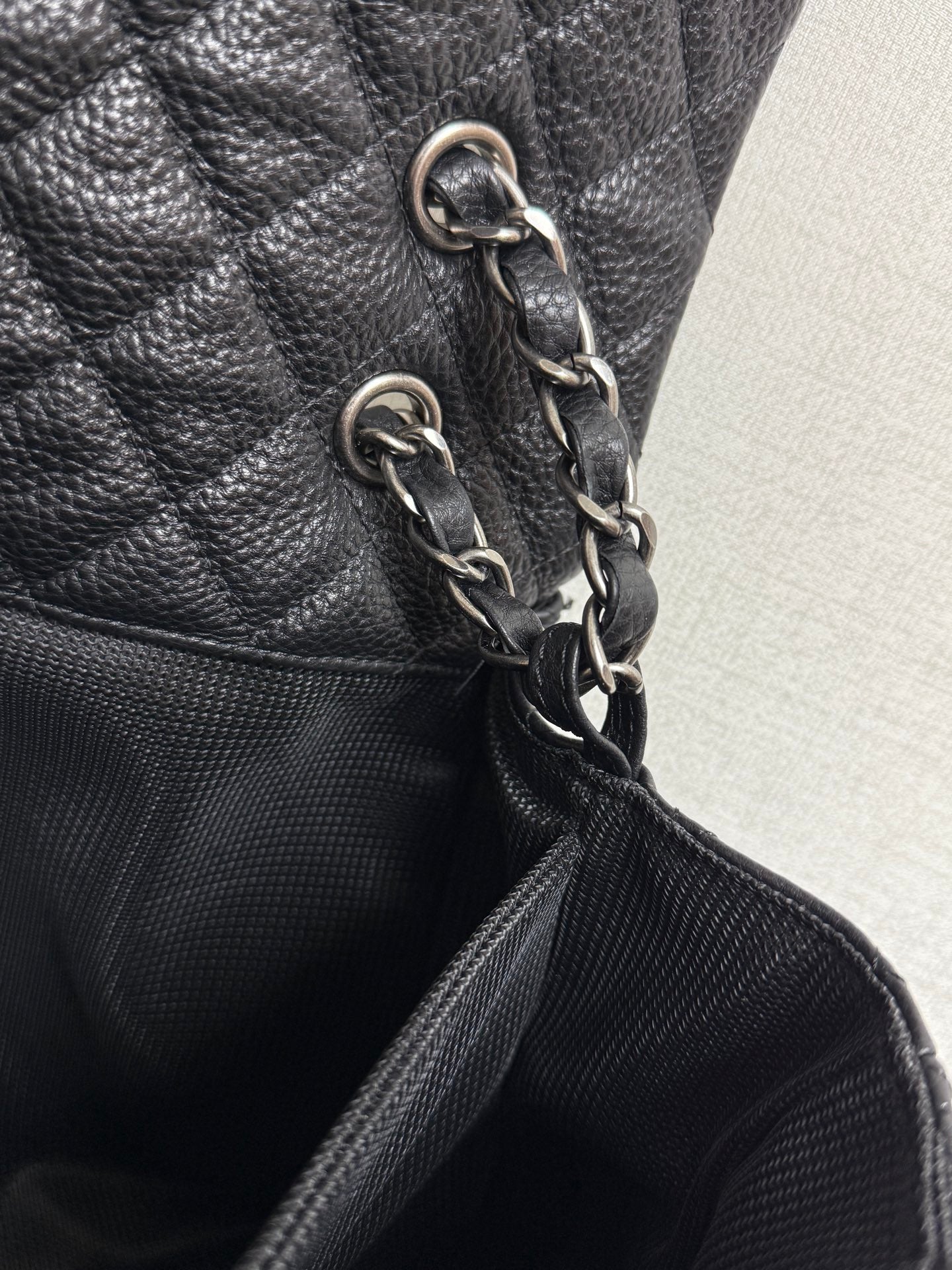 Chanel chain strap with silver-tone links on dark quilted leather bag.