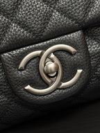 Chanel CC metal logo on dark quilted leather flap.