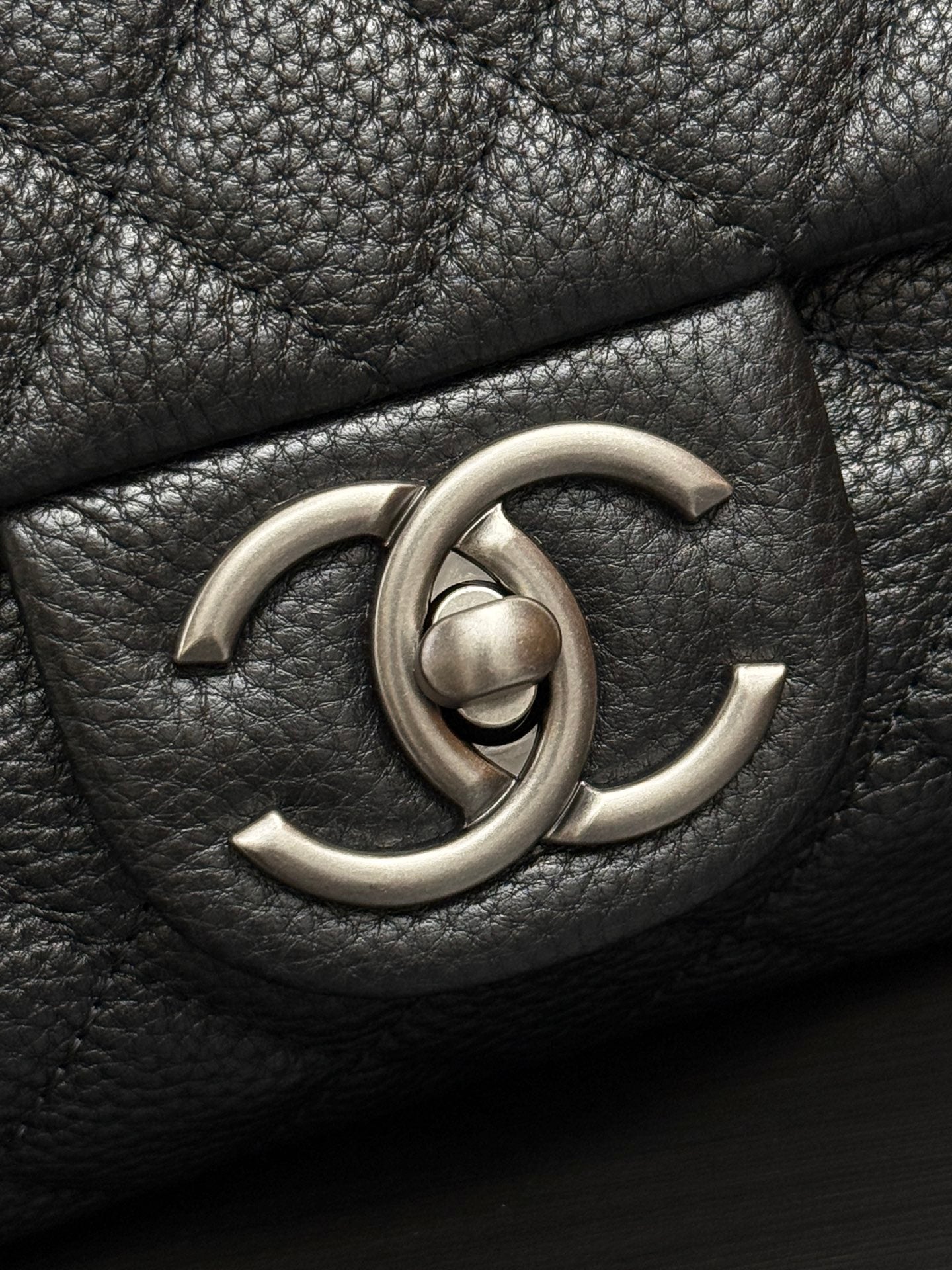 Chanel CC metal logo on dark quilted leather flap.