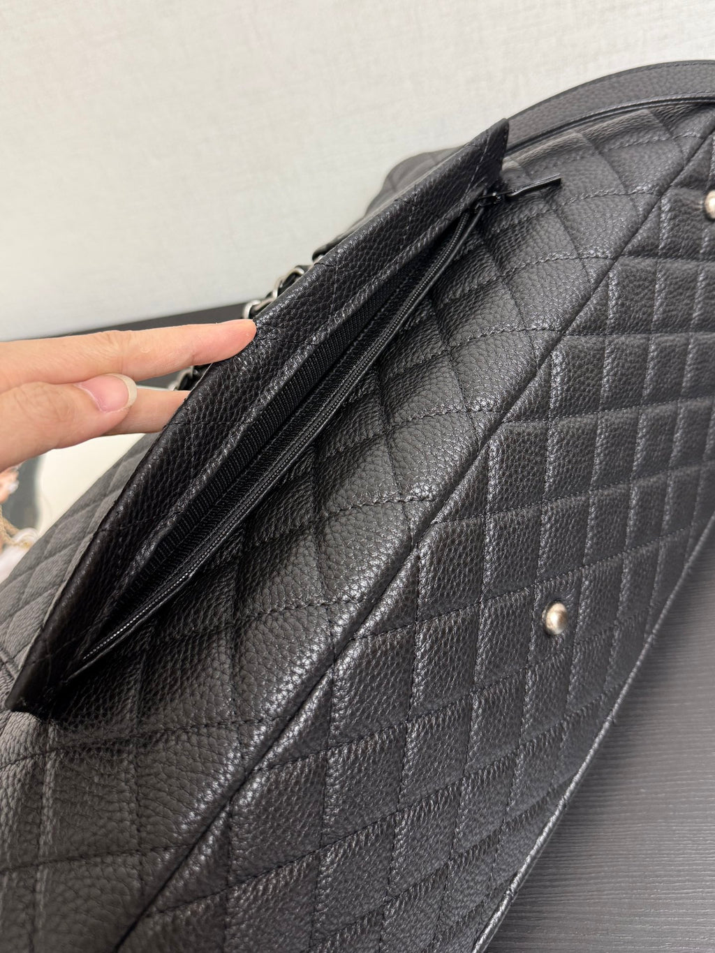 Chanel quilted shoulder bag opening with zipper and hand holding the flap edge.