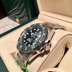 Rolex stainless steel diver watch with green bezel and black dial on beige cushion
