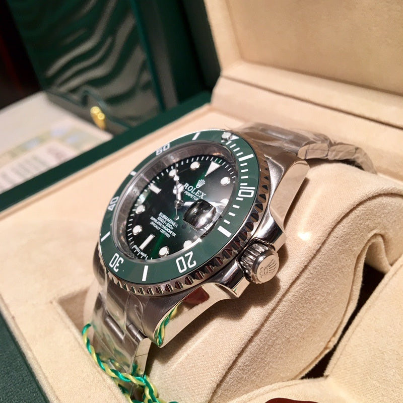 Rolex stainless steel diver watch with green bezel and black dial on beige cushion