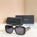 Black sunglasses with oversized rounded frames and dark purple tinted lenses, logo on temple
