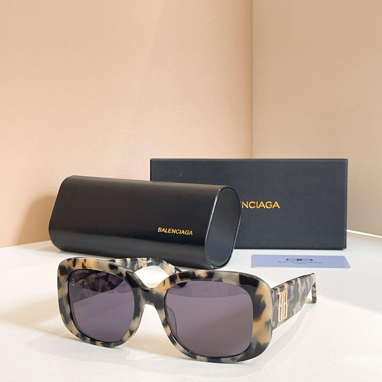 Tortoiseshell sunglasses with dark tinted lenses and chunky oversized frames, logo on temple