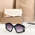 Octagonal sunglasses with black frames and purple-tinted lenses, gold-tone temples.