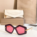 Octagonal sunglasses with dark frames and pink-tinted lenses, gold-tone temples.