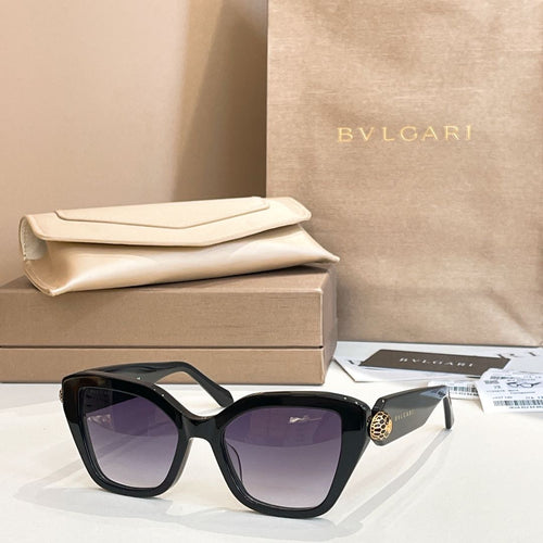 Black square glasses with dark lenses and gold-tone accent on the temple.