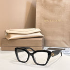Black square glasses with clear, lightly tinted lenses and gold-tone temple detail.