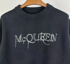 Dark knit sweater close-up with crew neck and McQUEEN logo on chest