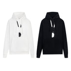 Pullover hoodies, one white and one black, with drawstring hood and hanging tag