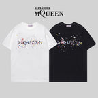 Two Alexander McQueen T-shirts in white and black with colorful splatter logo graphic