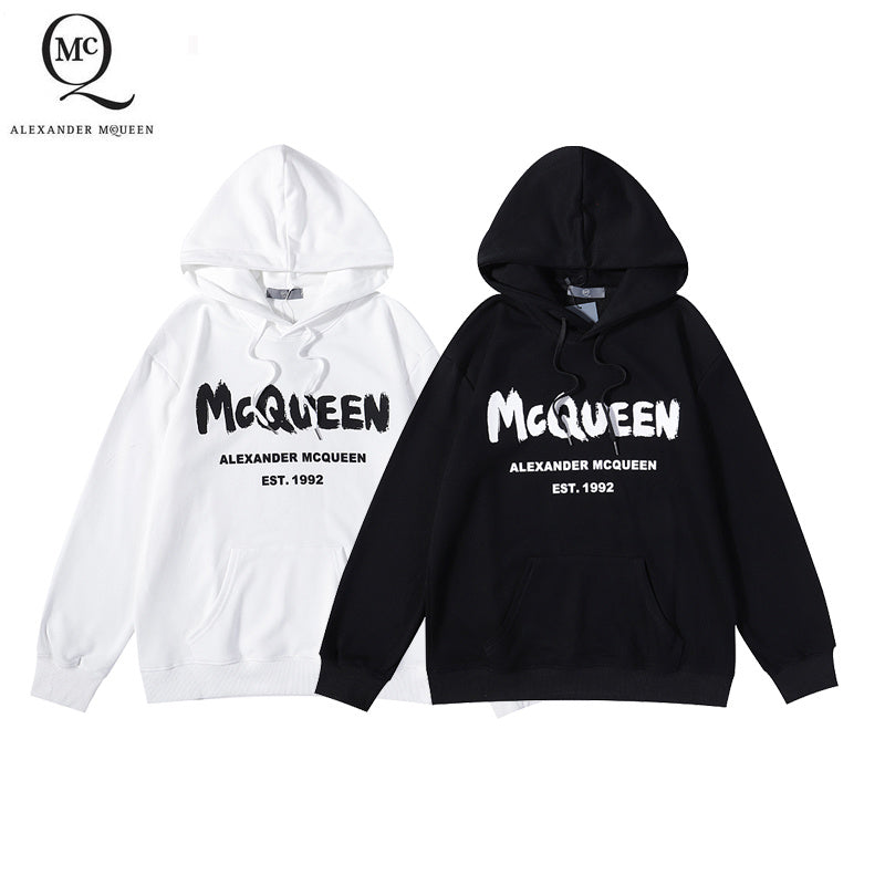 Two pullover hoodies, white and black, with McQueen logo graphic on chest.