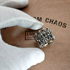 Silvertone ornate ring with raised floral design, held in a white glove