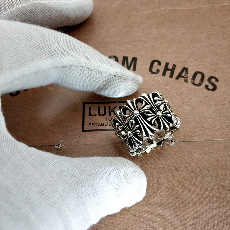 Silvertone ornate ring with raised floral design, held in a white glove