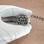 Silvertone ornate square ring with floral filigree on a white glove
