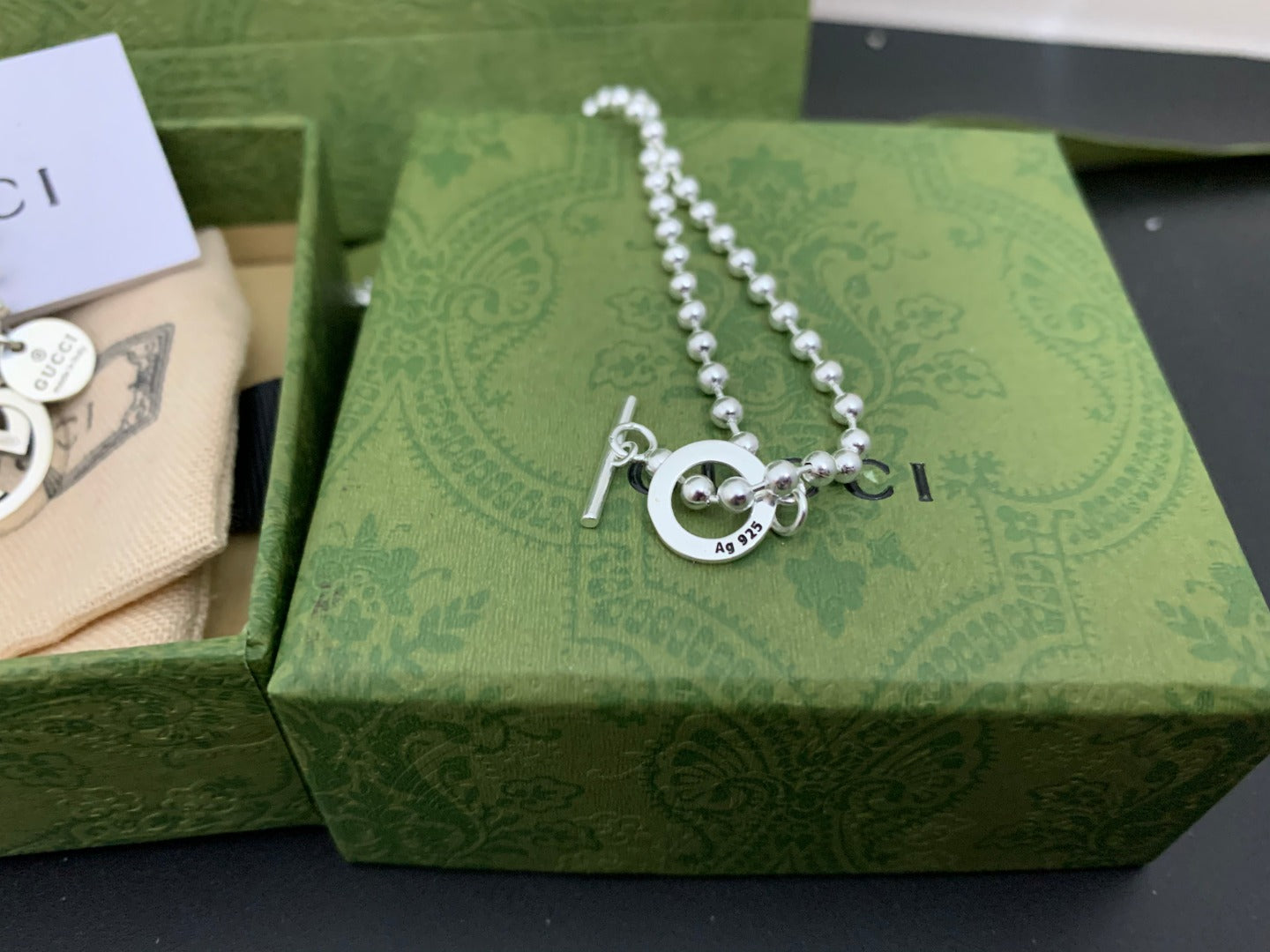 Silver chain necklace with round GUCCI logo pendant and two dangling letter charms