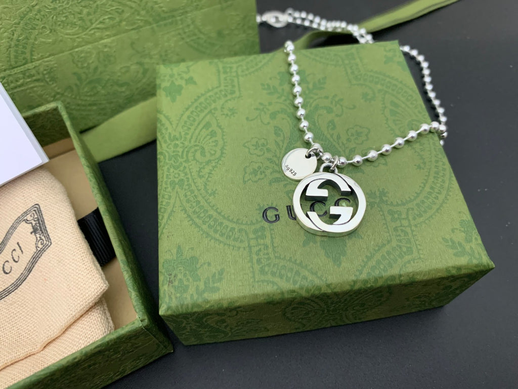 Silver chain necklace with round GUCCI logo pendant, clasp visible