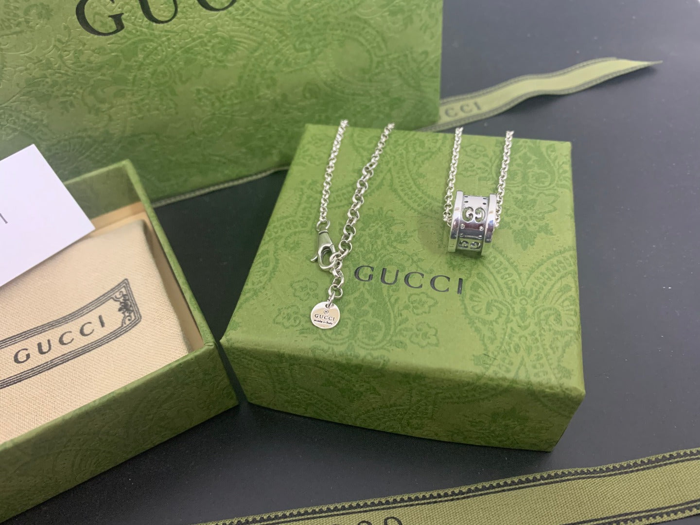 Silver Gucci pendant necklace with chain and square clasp pendant on green box
