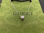 Silver Gucci pendant necklace on green Gucci pouch with large logo