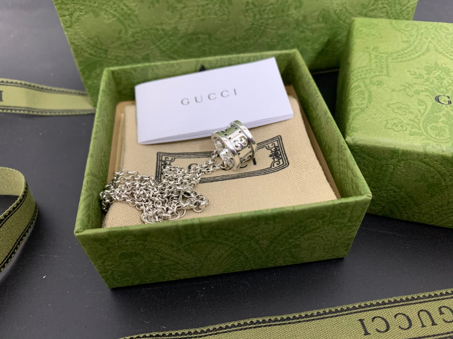 Silver Gucci pendant necklace with chain on beige insert inside green gift box