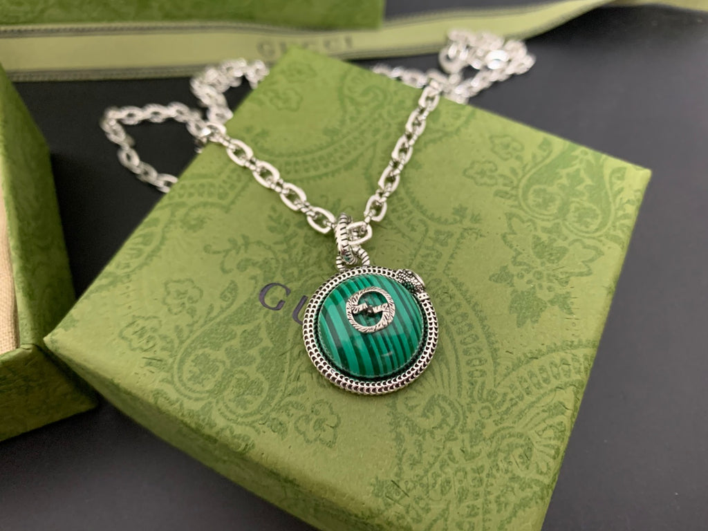 Gucci pendant necklace close-up with green round medallion on silver chain