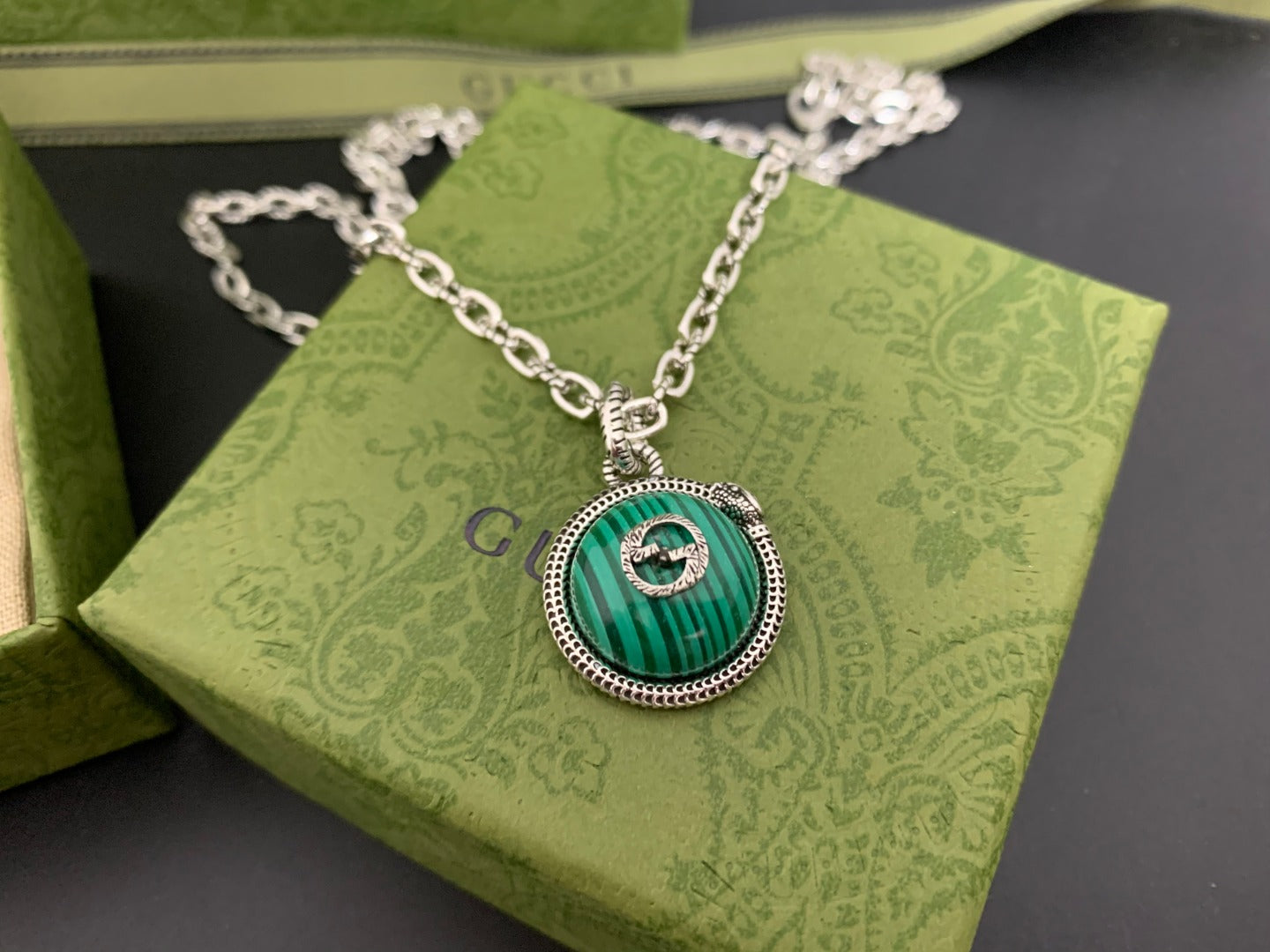 Gucci pendant necklace close-up with green round medallion on silver chain